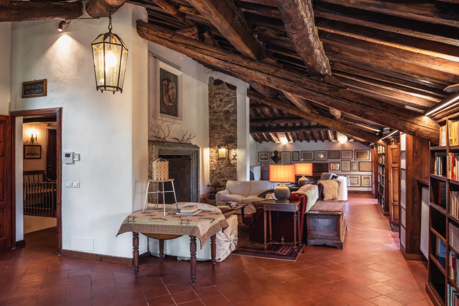 Rustic living room interior featuring exposed wooden beams, a cozy seating area with plush sofas, a stone fireplace, and built-in bookshelves, creating a warm and inviting atmosphere. | Only on SopranoVillas