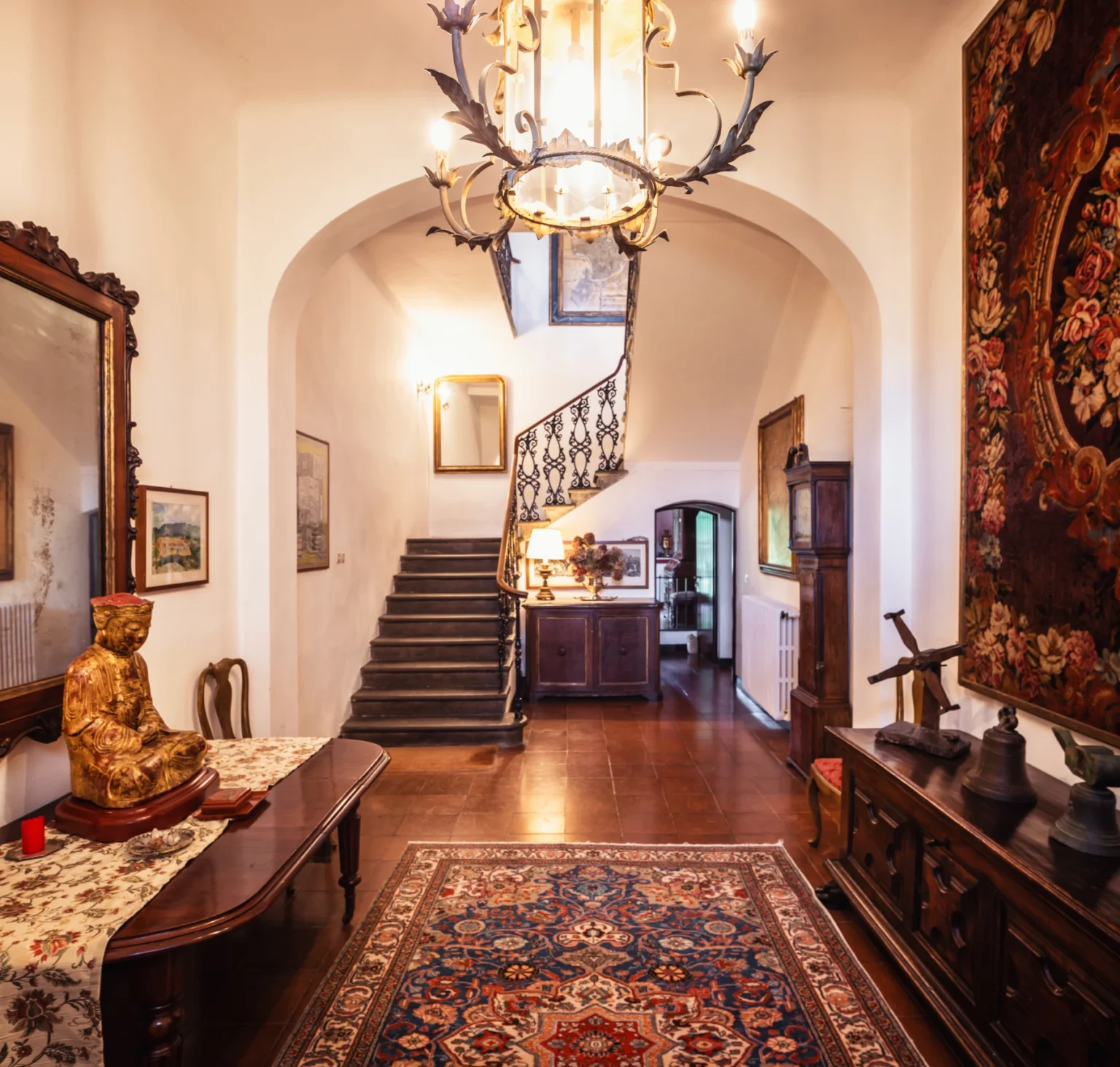 Elegant entrance hall featuring a staircase, vintage decor, and antique furnishings, creating a warm and inviting atmosphere. | Only on SopranoVillas
