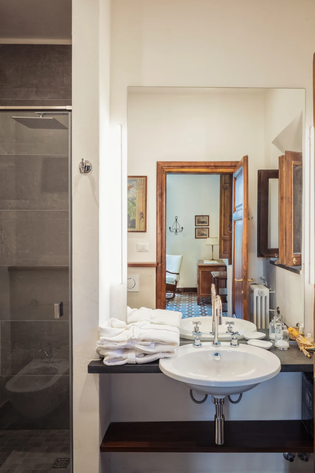 Bright and modern bathroom featuring a shower, elegant fixtures, and a view into a well-decorated room with wooden accents and artwork. Ideal for showcasing interior design and home decor inspiration. | Only on SopranoVillas
