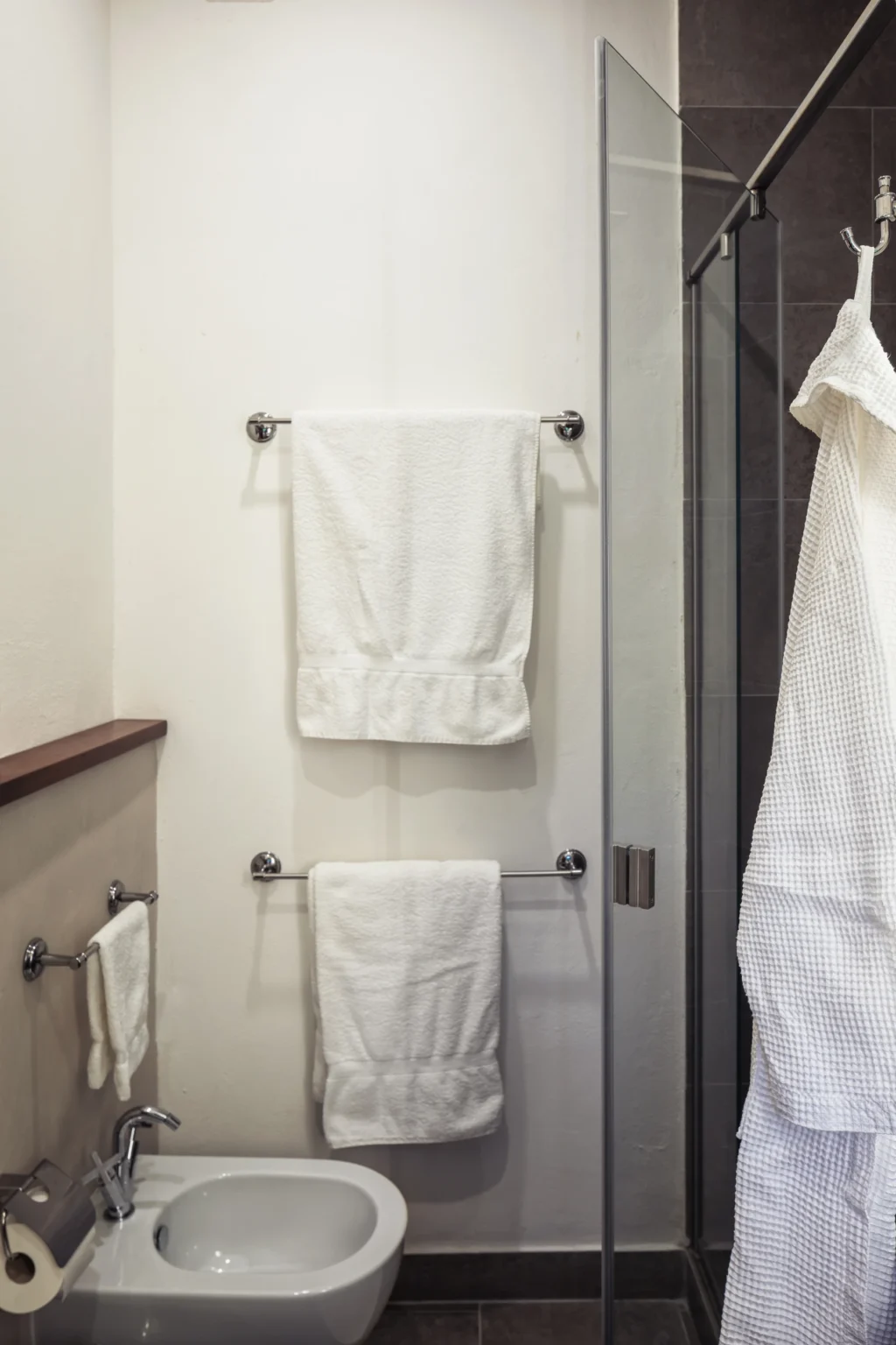 Modern bathroom with neatly arranged white towels hanging on chrome racks, featuring a clean and minimalist design. | Only on SopranoVillas