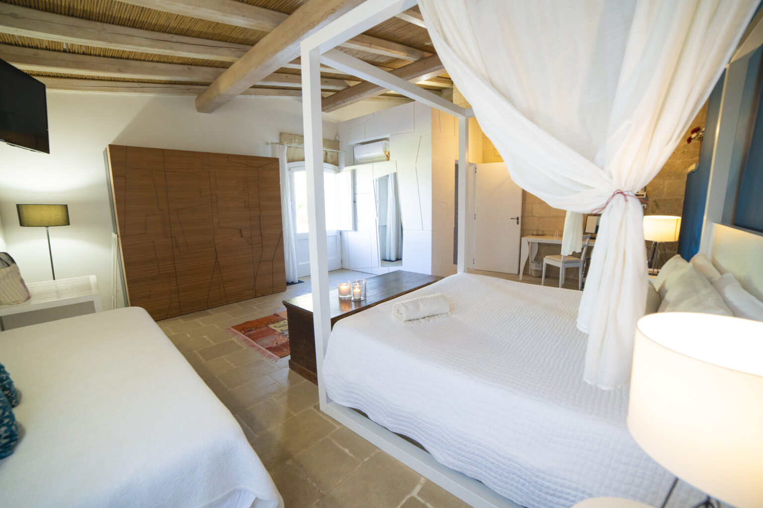 Cozy bedroom featuring a modern four-poster bed with white linens, a comfortable single bed, stylish wooden furniture, and natural light from large windows. The room is decorated with soft colors and contemporary design elements, creating a relaxing atmosphere. | Only on SopranoVillas
