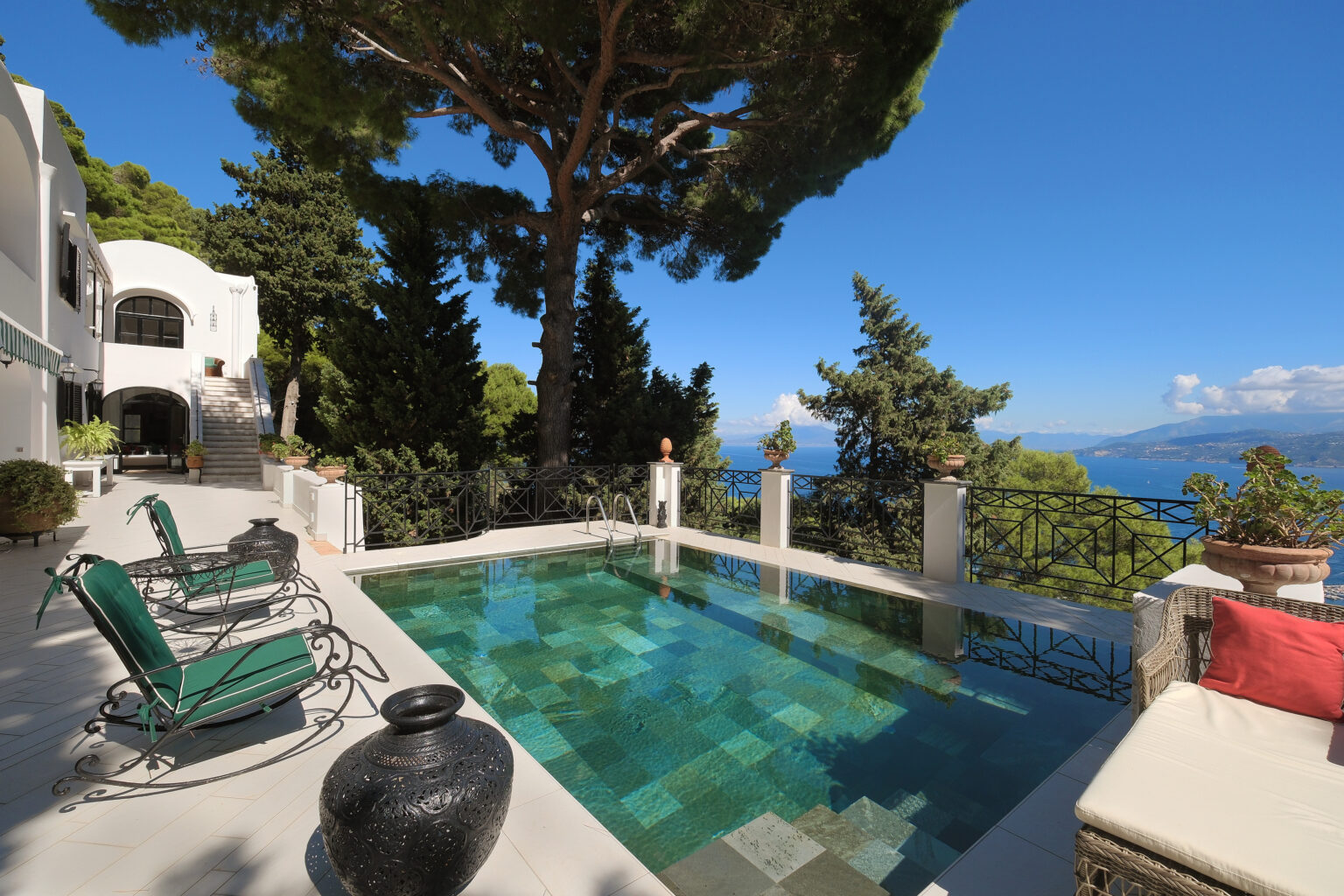 Luxury villa with a stunning infinity pool overlooking the ocean, surrounded by lush greenery and comfortable outdoor seating. Ideal for relaxation and enjoying picturesque views. | Only on SopranoVillas