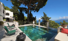 Luxury villa with a stunning infinity pool overlooking the ocean, surrounded by lush greenery and comfortable outdoor seating. Ideal for relaxation and enjoying picturesque views.