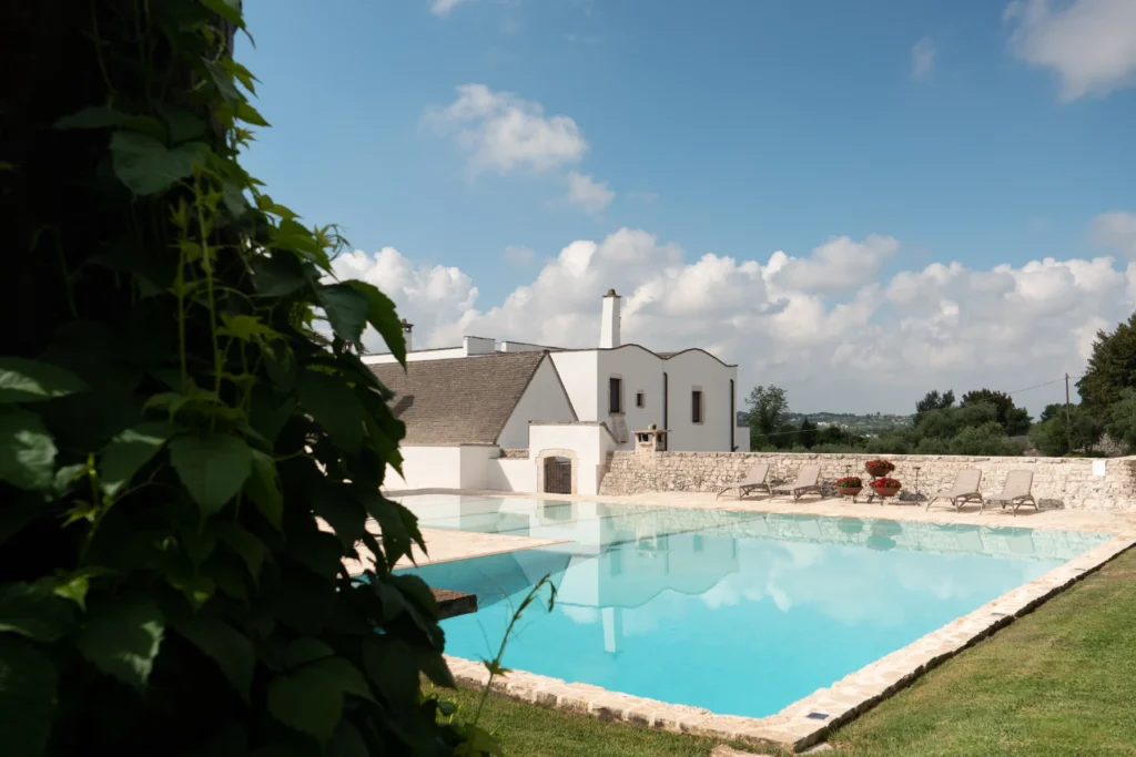 Modern villa with a swimming pool surrounded by lush greenery and a clear blue sky, ideal for relaxation and outdoor activities. | Only on SopranoVillas
