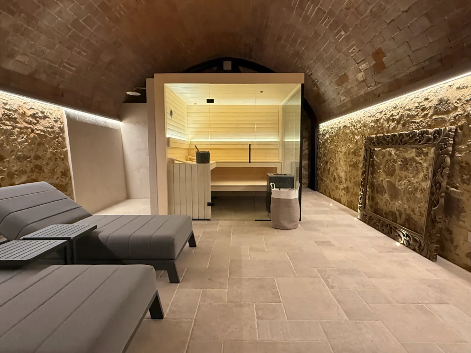 Modern spa interior featuring a sauna, comfortable lounge chairs, and natural stone walls, illuminated by soft ambient lighting. Ideal for relaxation and wellness. | Only on SopranoVillas