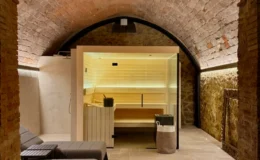 Modern wellness spa interior featuring a brick archway, sleek lounge chairs, and a sauna area with warm lighting, designed for relaxation and comfort.