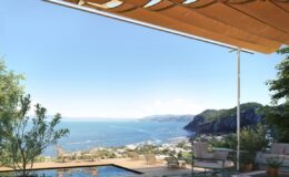 Scenic view from a modern terrace overlooking a tranquil sea and coastal landscape, featuring a swimming pool and comfortable seating under a stylish awning.