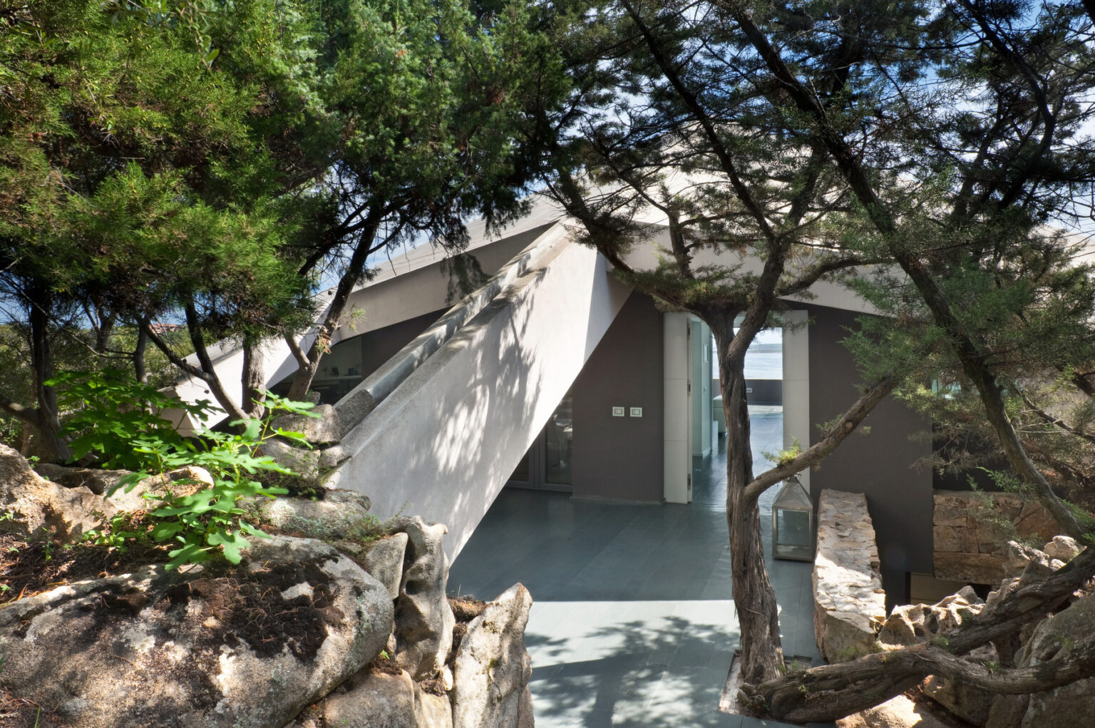 Modern architectural design featuring a unique angular structure nestled among trees, showcasing a blend of natural elements and contemporary aesthetics. | Only on SopranoVillas