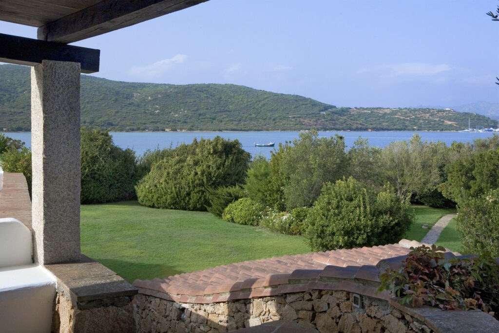 Scenic view of a lush green garden leading to a tranquil lake surrounded by hills under a clear blue sky. Ideal for nature lovers and outdoor enthusiasts. | Only on SopranoVillas