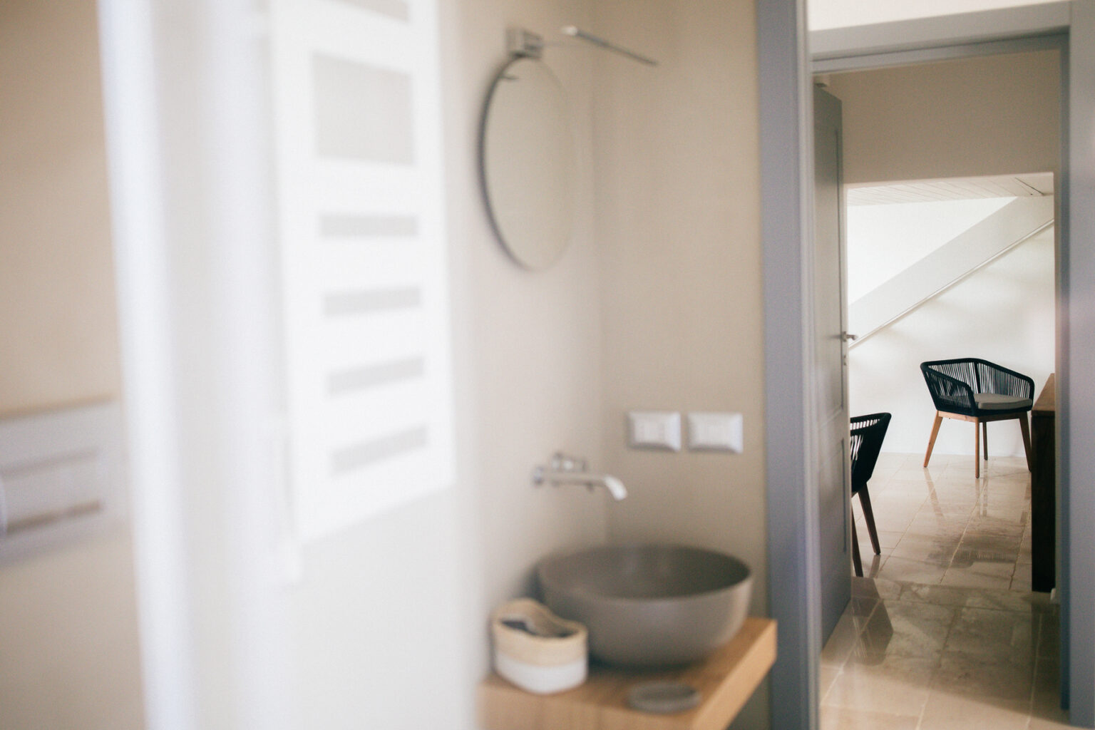 Modern bathroom interior with a stylish sink and mirror, leading to a cozy seating area in a contemporary home. | Only on SopranoVillas