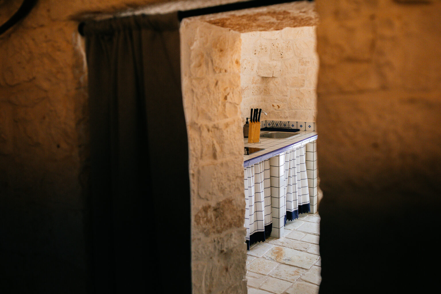Interior view of a rustic stone room with a wooden table featuring various utensils, illuminated by natural light, creating a warm and inviting atmosphere. | Only on SopranoVillas