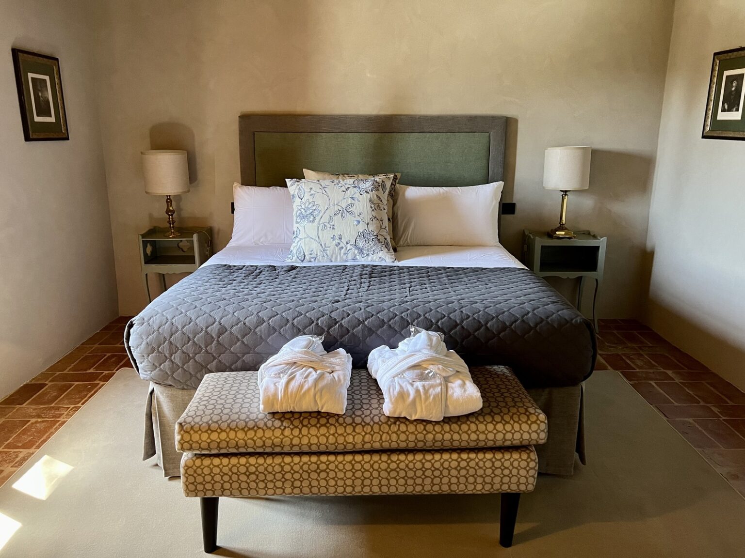 Cozy bedroom with a king-sized bed, decorative pillows, and two bedside lamps, featuring a comfortable ottoman with folded towels at the foot of the bed. | Only on SopranoVillas
