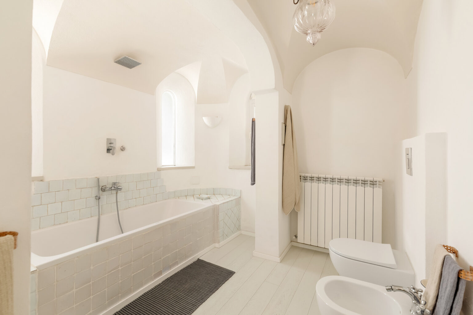 Spacious modern bathroom featuring a bathtub, shower, and minimalist design with soft lighting and neutral colors. | Only on SopranoVillas
