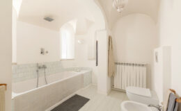 Spacious modern bathroom featuring a bathtub, shower, and minimalist design with soft lighting and neutral colors.
