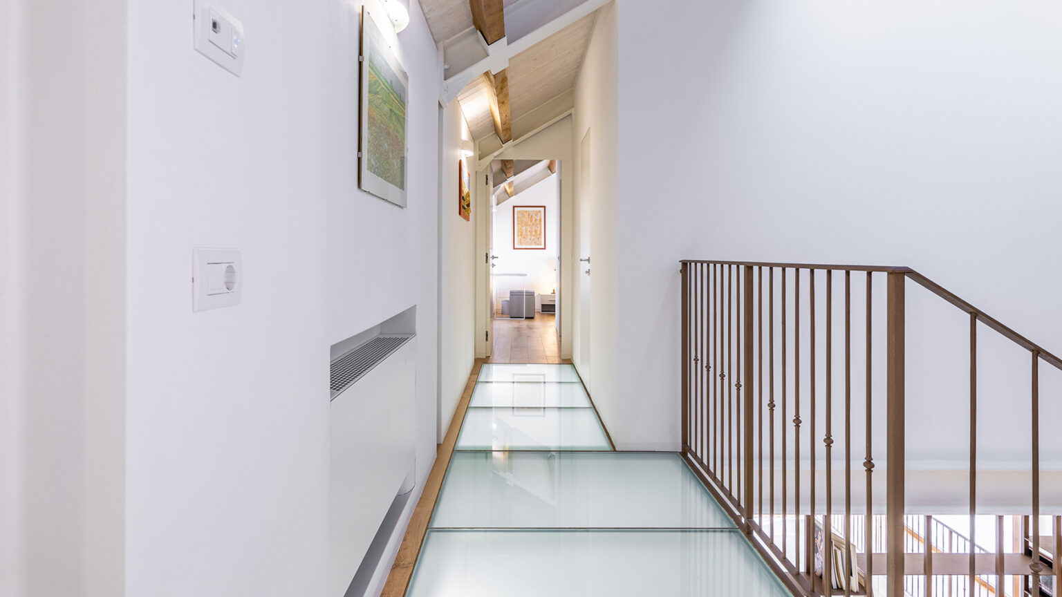 Modern interior hallway featuring a glass floor, white walls, and wooden accents, leading to a well-lit room. The design combines contemporary elements with natural light, enhancing the spacious feel of the area. | Only on SopranoVillas