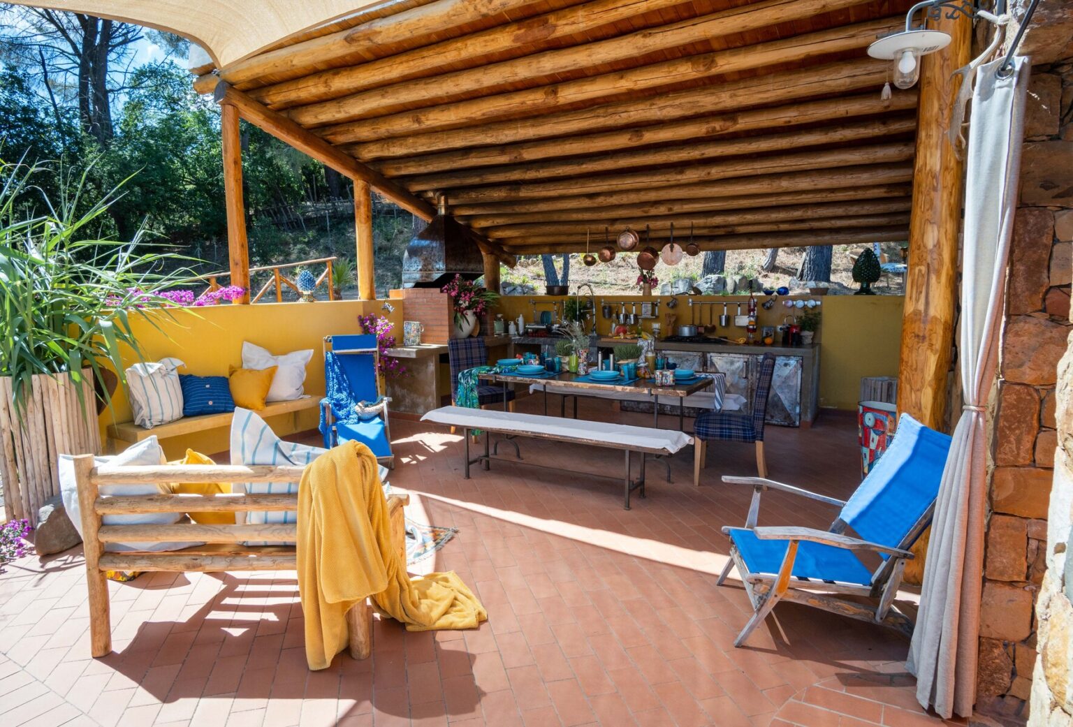 Cozy outdoor patio with wooden beams, colorful seating, and a bar area, surrounded by greenery, perfect for relaxation and social gatherings. | Only on SopranoVillas