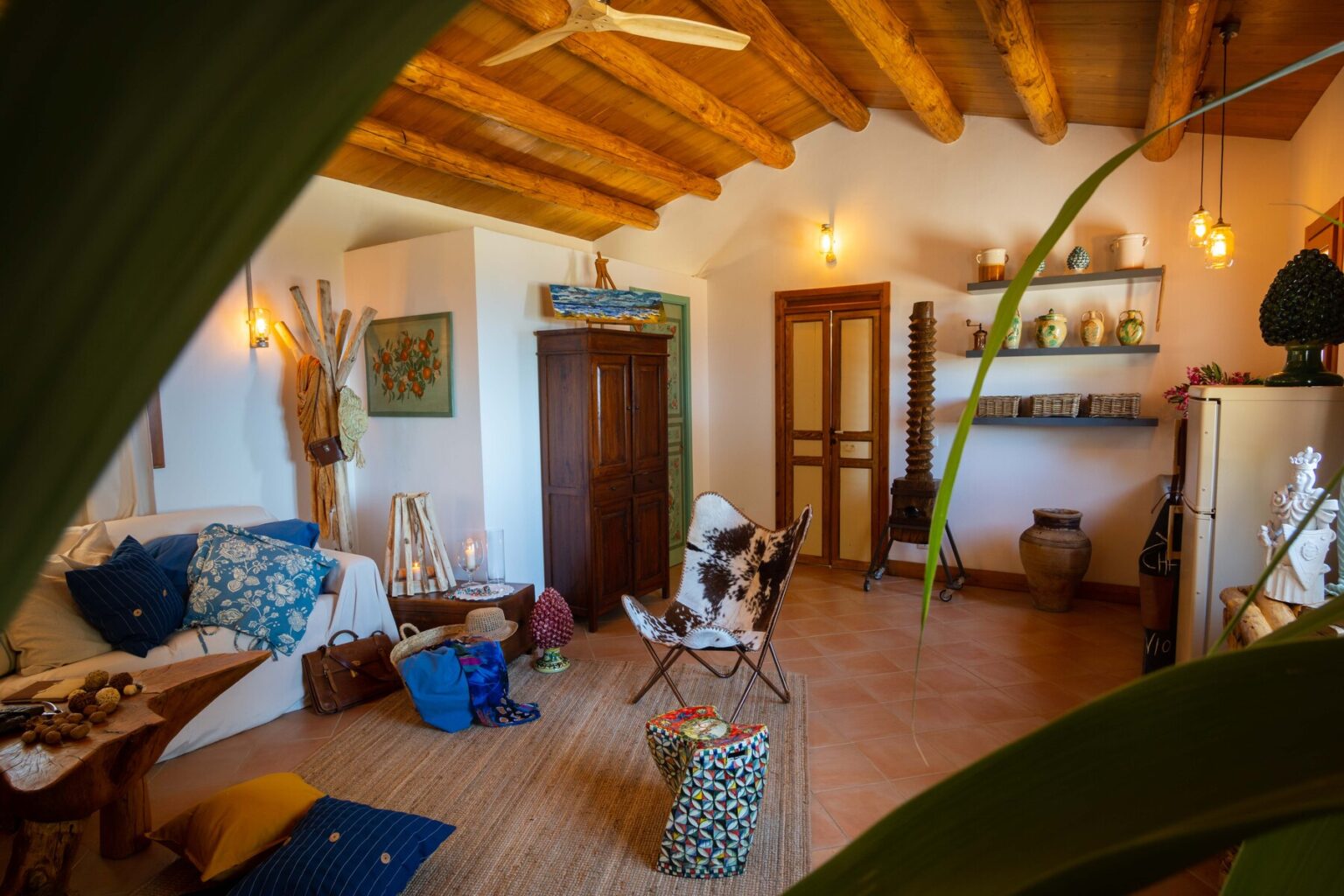 Cozy interior of a rustic living room featuring wooden beams, comfortable seating, decorative plants, and various art pieces, creating a warm and inviting atmosphere. | Only on SopranoVillas