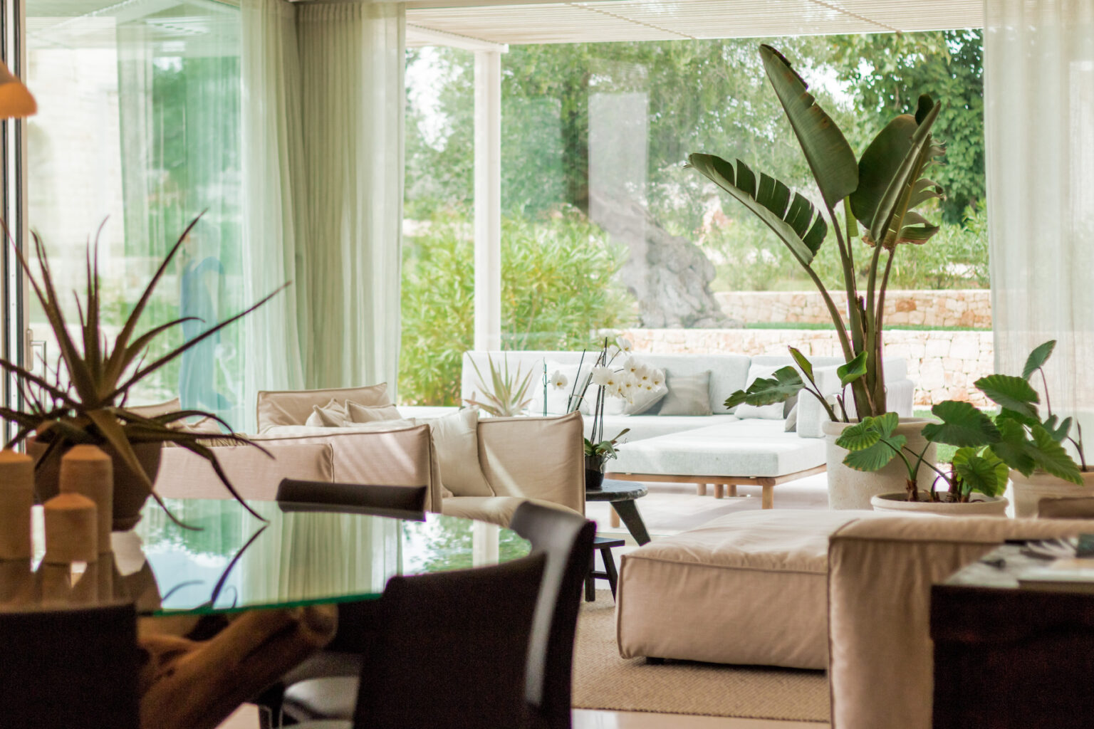 Bright and airy modern living room featuring large windows, comfortable seating, and indoor plants, creating a serene and inviting atmosphere. | Only on SopranoVillas