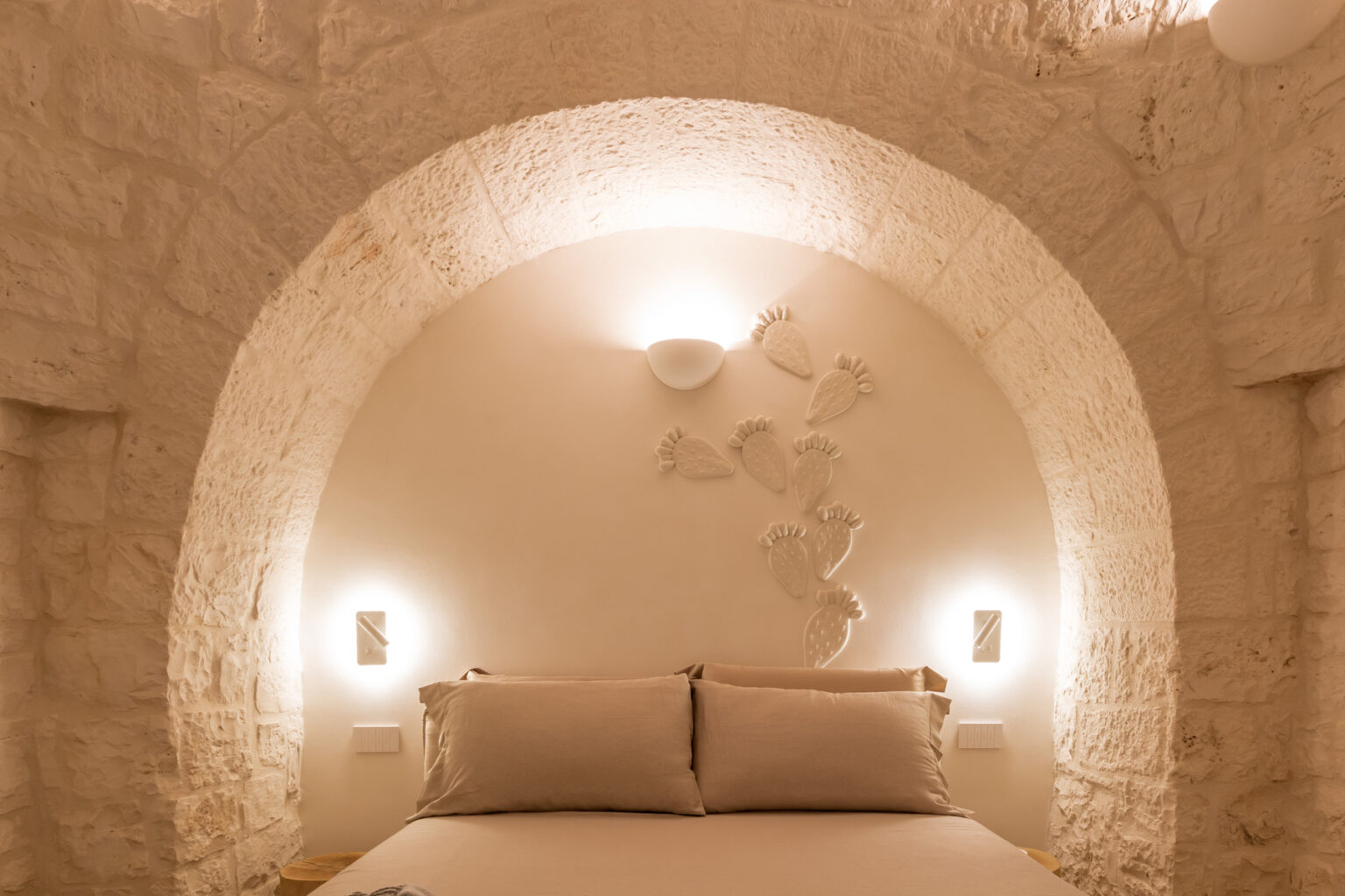 Cozy bedroom interior featuring a curved stone wall, soft lighting, and minimalist decor, creating a serene and inviting atmosphere. | Only on SopranoVillas