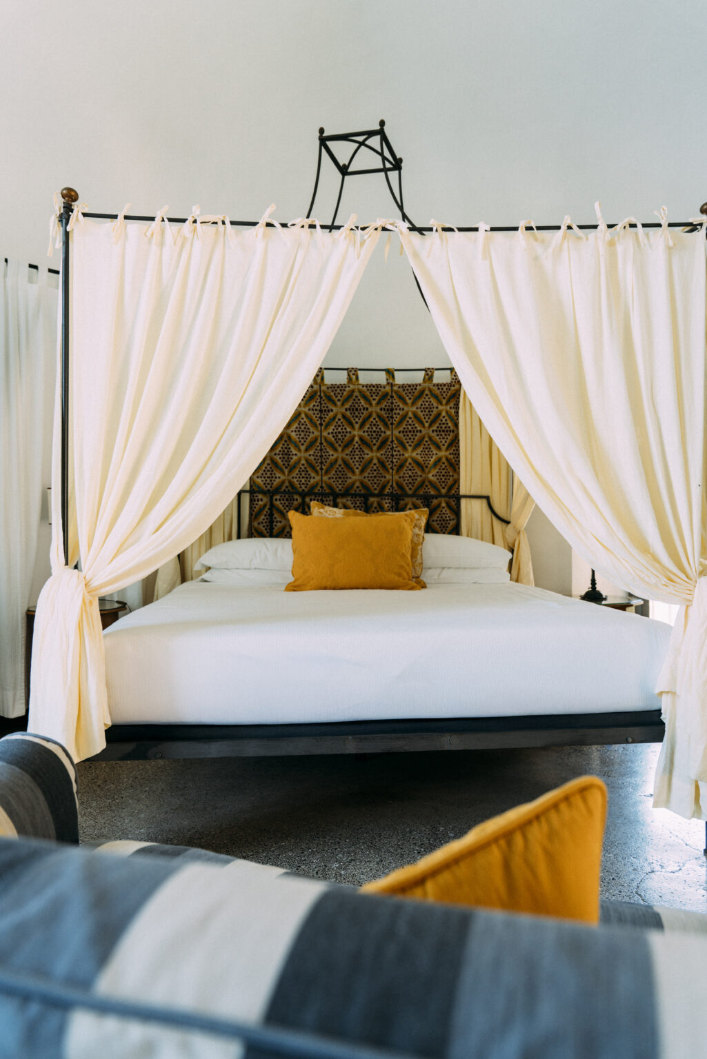Luxurious bedroom in an Italian villa rental featuring a four-poster bed with elegant drapes and a decorative headboard, ideal for a relaxing getaway. | Only on SopranoVillas