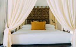Luxurious bedroom in an Italian villa rental featuring a four-poster bed with elegant drapes and a decorative headboard, ideal for a relaxing getaway.