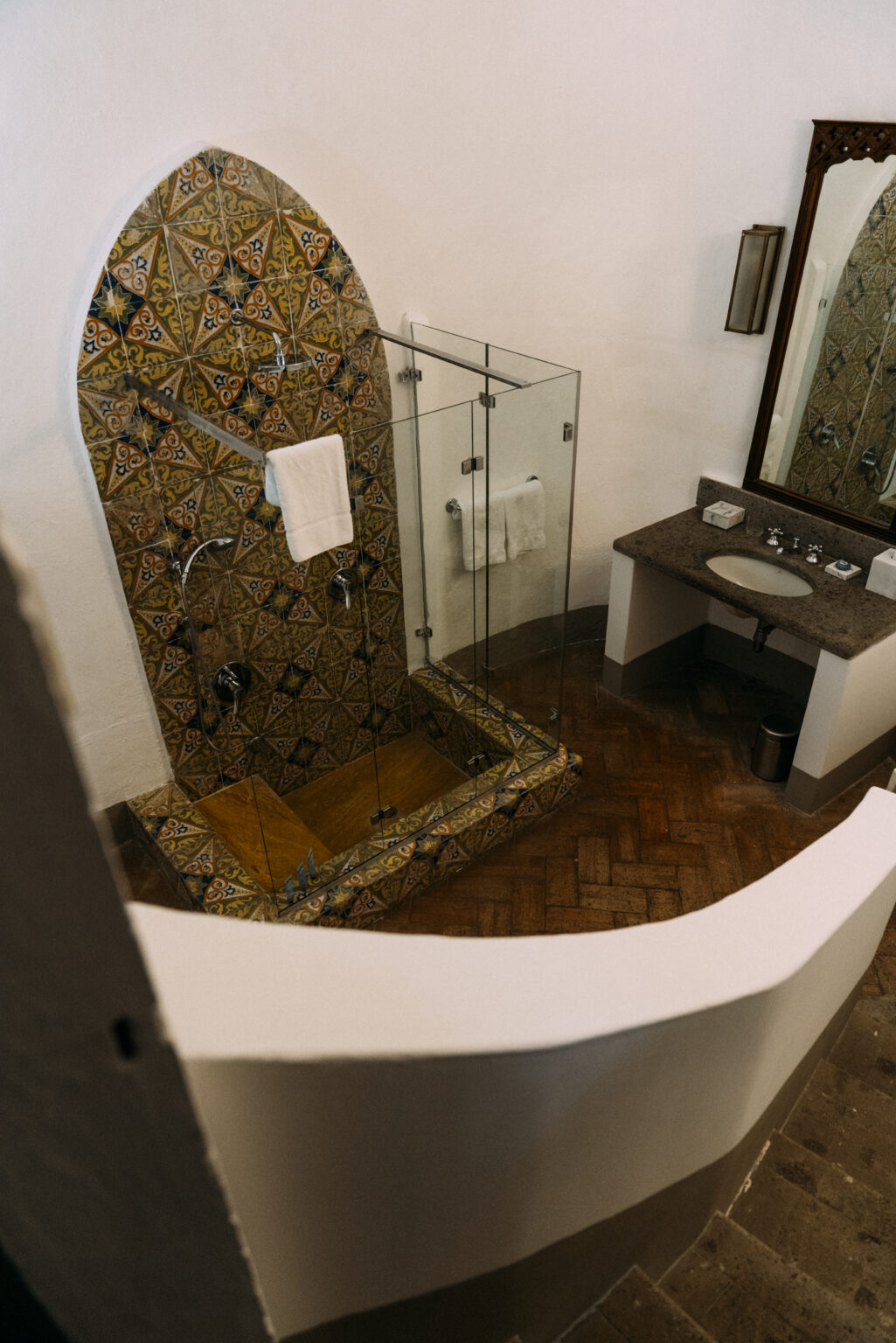 Luxurious bathroom featuring a spacious glass shower, intricate tiled walls, and elegant wooden flooring, showcasing upscale amenities in a rental villa in Italy. | Only on SopranoVillas