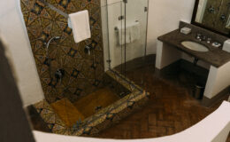 Luxurious bathroom featuring a spacious glass shower, intricate tiled walls, and elegant wooden flooring, showcasing upscale amenities in a rental villa in Italy.