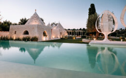 Luxury villa with trullo architecture, serene swimming pool, and landscaped gardens at dusk. Ideal for vacation rentals or destination weddings.