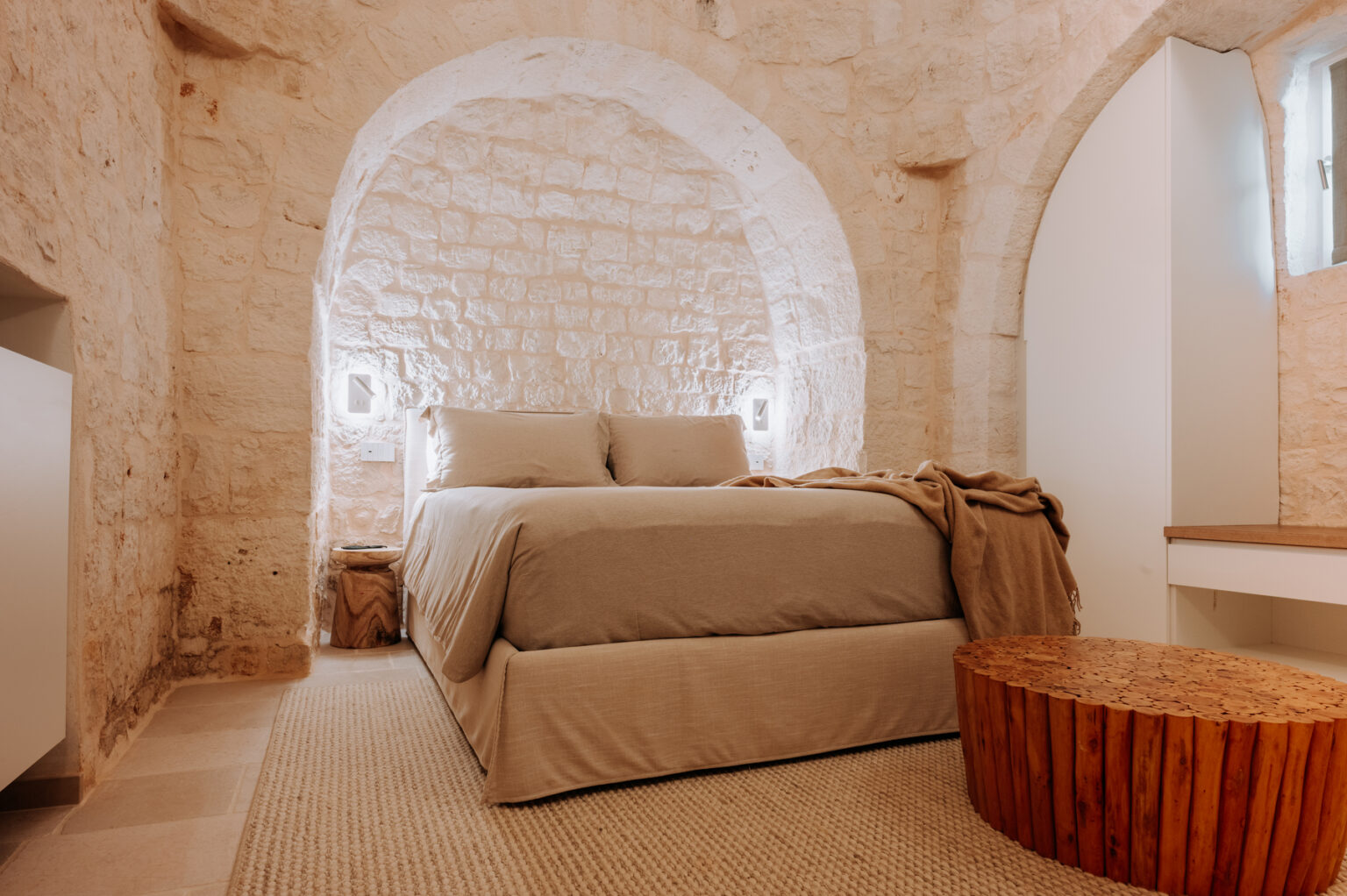 Cozy bedroom featuring a stone wall design, a comfortable bed with neutral bedding, and a rustic wooden side table, creating a warm and inviting atmosphere. | Only on SopranoVillas