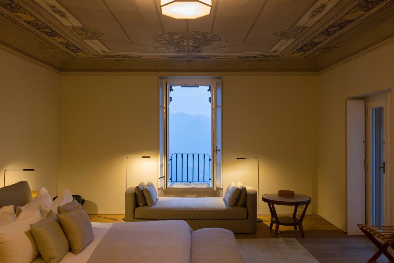 Luxury villa bedroom in Italy featuring elegant decor, a large window with scenic views, and stylish furnishings, ideal for a relaxing getaway. | Only on SopranoVillas