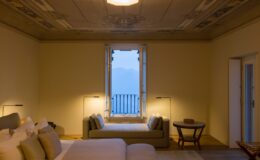 Luxury villa bedroom in Italy featuring elegant decor, a large window with scenic views, and stylish furnishings, ideal for a relaxing getaway.