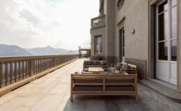 Elegant outdoor terrace featuring stylish wooden furniture, overlooking scenic mountains under a soft cloudy sky. Ideal for relaxation and enjoying nature.