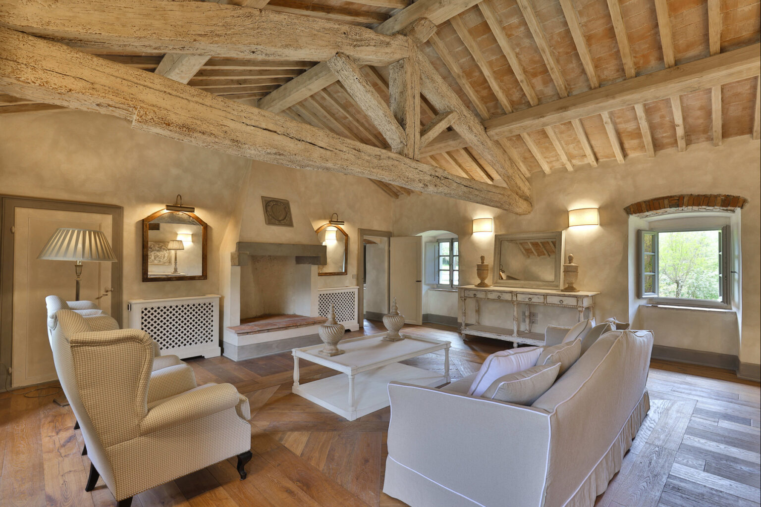 Spacious and elegantly designed living room with high wooden beams, comfortable seating, and natural light streaming through large windows, showcasing a blend of rustic charm and modern aesthetics. | Only on SopranoVillas
