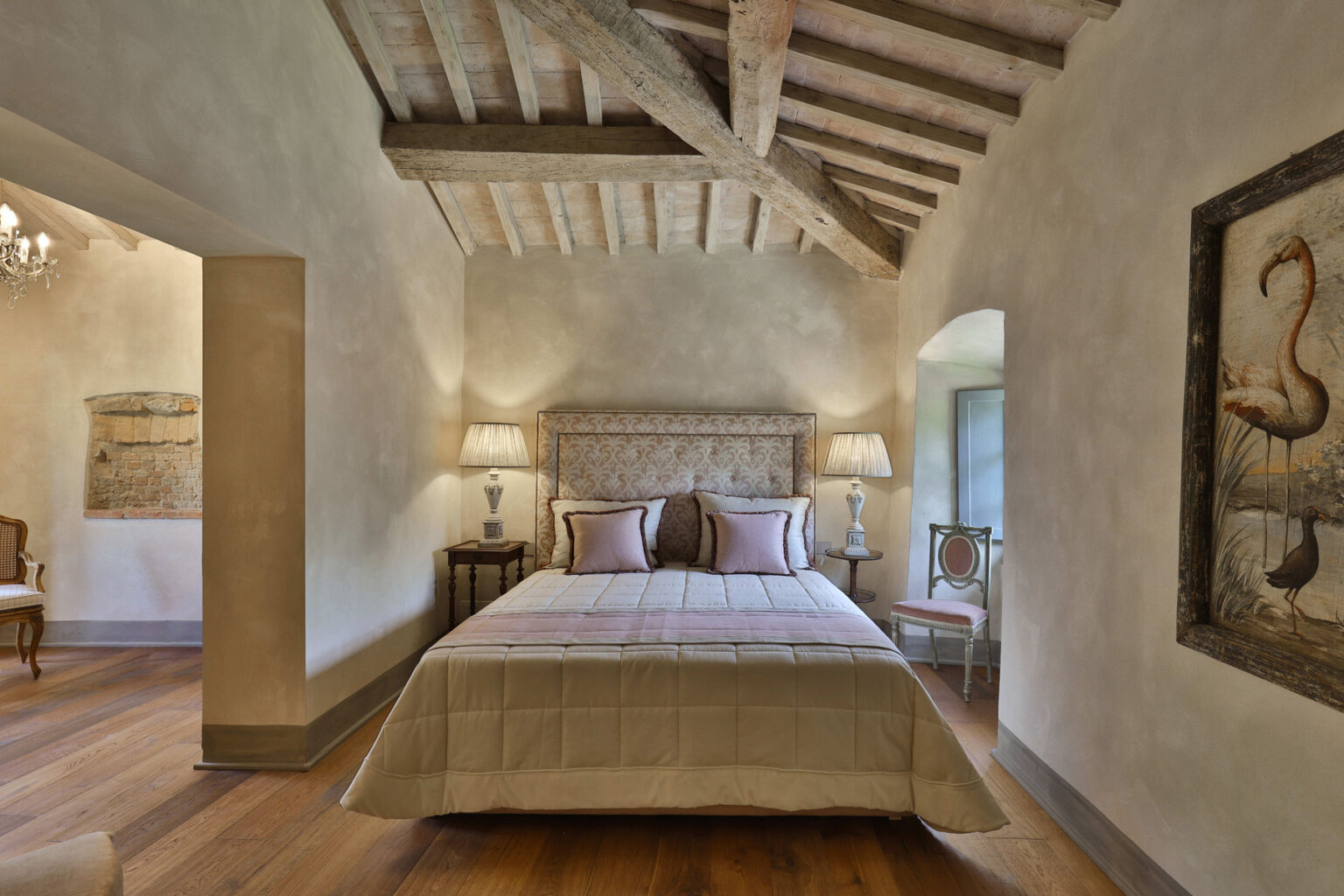 Cozy bedroom featuring a wooden beam ceiling, a plush bed with decorative pillows, and elegant bedside lamps. The soft color palette and rustic decor create a warm, inviting atmosphere, ideal for relaxation. | Only on SopranoVillas