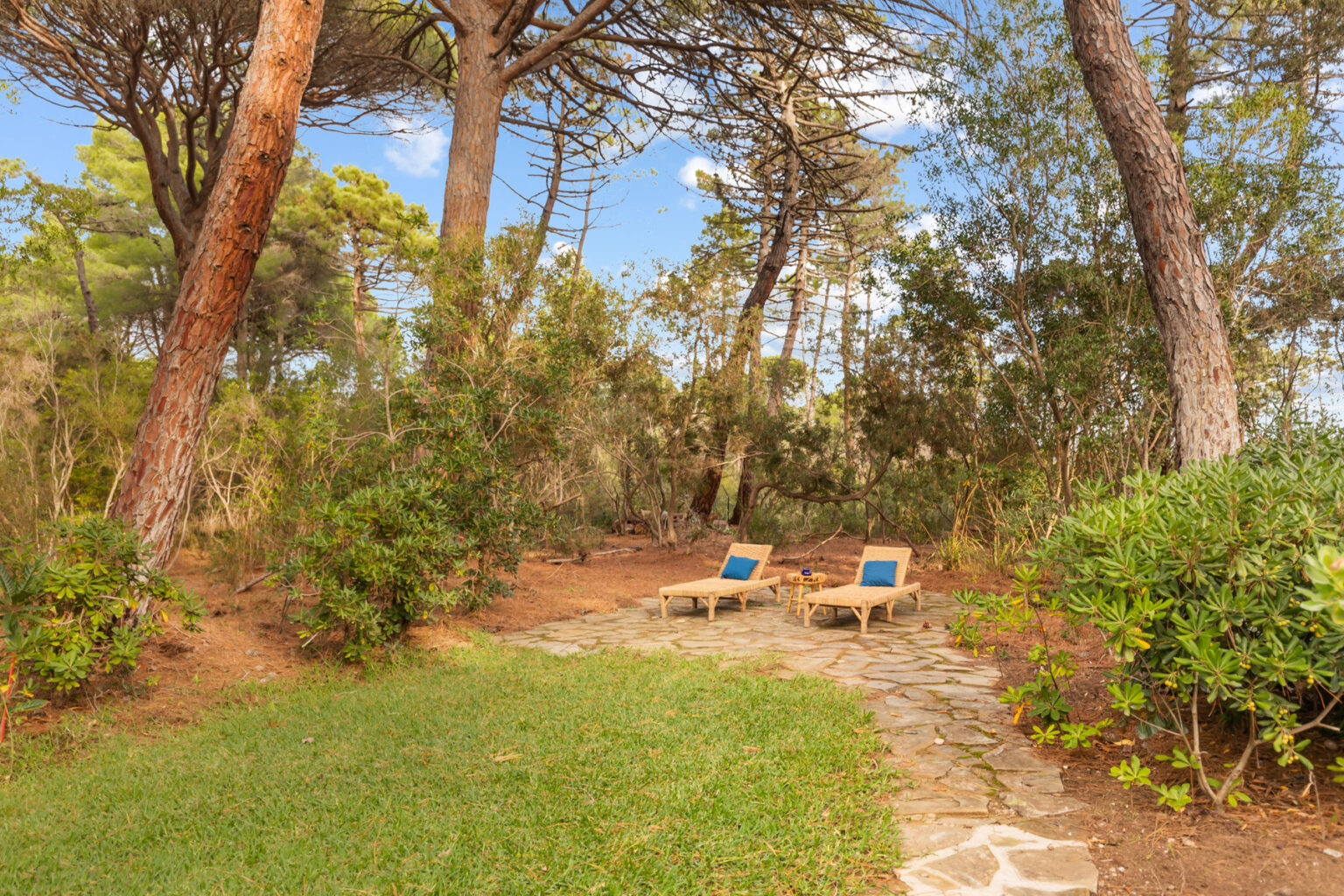 Relaxing outdoor space with two lounge chairs surrounded by lush greenery and trees, ideal for enjoying nature and tranquility. | Only on SopranoVillas