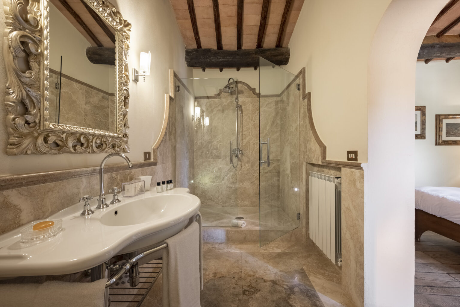 Luxurious bathroom featuring a modern shower with glass enclosure, elegant marble finishes, a stylish sink with vintage-inspired fixtures, and decorative mirrors, creating a sophisticated and relaxing atmosphere. | Only on SopranoVillas