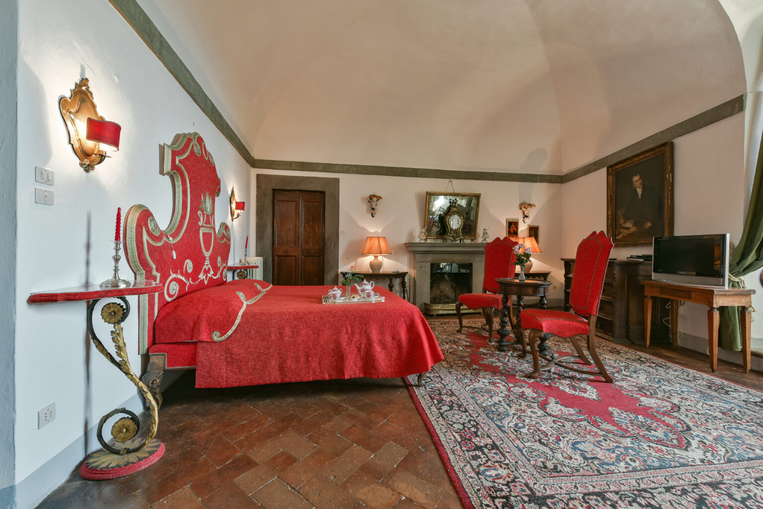 Luxurious hotel room featuring a red-themed decor with a decorative bed, elegant furnishings, and a vintage rug, creating a cozy and inviting atmosphere. | Only on SopranoVillas