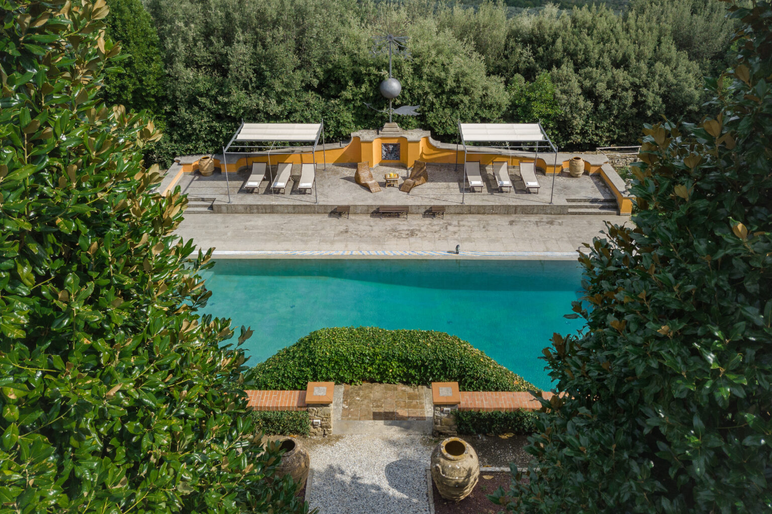 Aerial view of a luxurious outdoor pool surrounded by lush greenery and sun loungers, featuring a serene water surface and elegant landscaping, ideal for relaxation and leisure. | Only on SopranoVillas