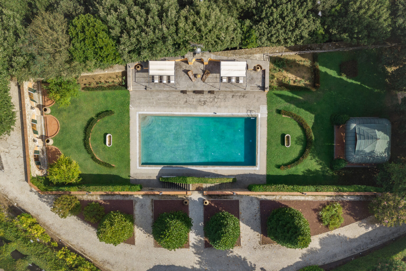 Aerial view of a luxurious backyard featuring a large swimming pool, surrounded by neatly landscaped greenery, seating areas, and a gazebo. Ideal for outdoor relaxation and entertaining. | Only on SopranoVillas