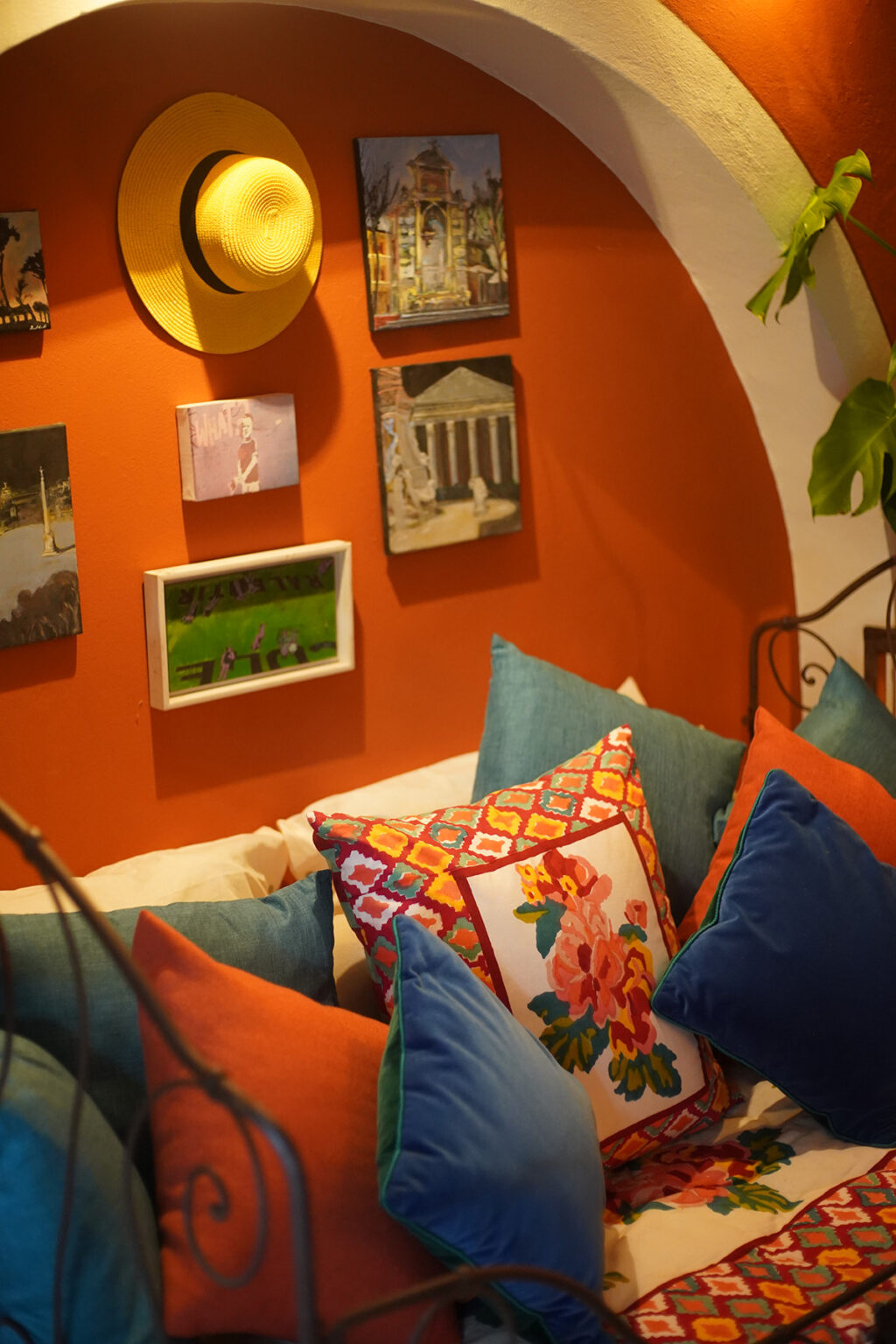 Cozy corner featuring colorful throw pillows on a white sofa against an orange wall adorned with framed artwork, creating a vibrant and inviting atmosphere. | Only on SopranoVillas