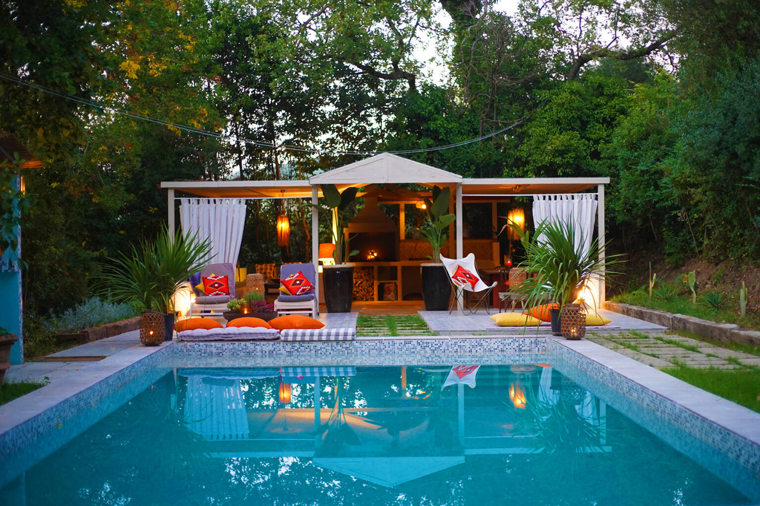 Outdoor pool area featuring a modern gazebo with comfortable seating, vibrant cushions, and lush greenery surrounding the tranquil setting. Ideal for relaxation and entertaining. | Only on SopranoVillas