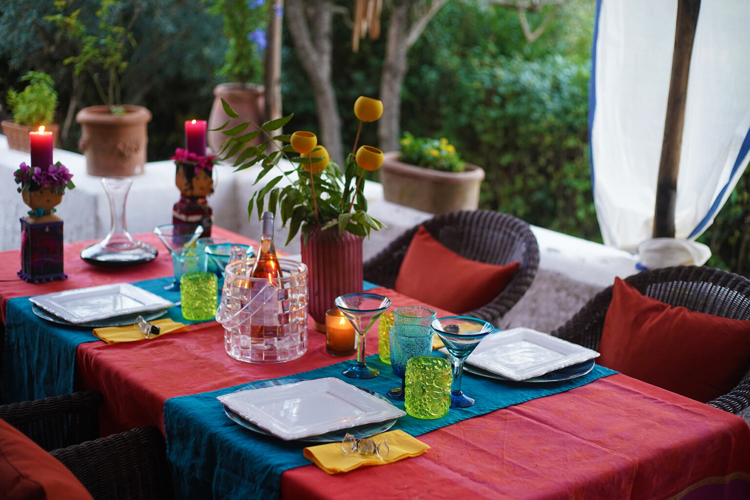 Colorful outdoor dining setup featuring vibrant table linens, decorative glassware, and floral centerpieces, creating an inviting atmosphere for gatherings and celebrations. | Only on SopranoVillas
