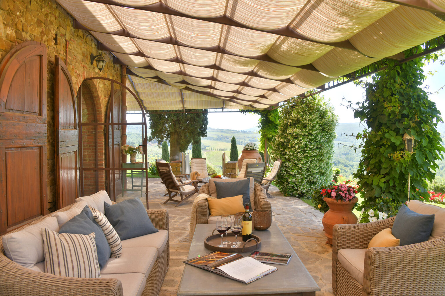 Elegant outdoor patio with comfortable seating, decorative cushions, and a scenic view of lush greenery, perfect for relaxation and entertaining. | Only on SopranoVillas