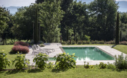 Serene outdoor pool surrounded by lush greenery and landscaped gardens, featuring comfortable lounge chairs and vibrant flowers, ideal for relaxation and leisure.