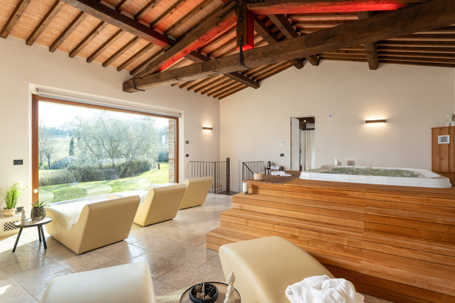 Spacious modern living area with wooden beams, large windows, and a hot tub, featuring minimalist furniture and scenic garden views. | Only on SopranoVillas