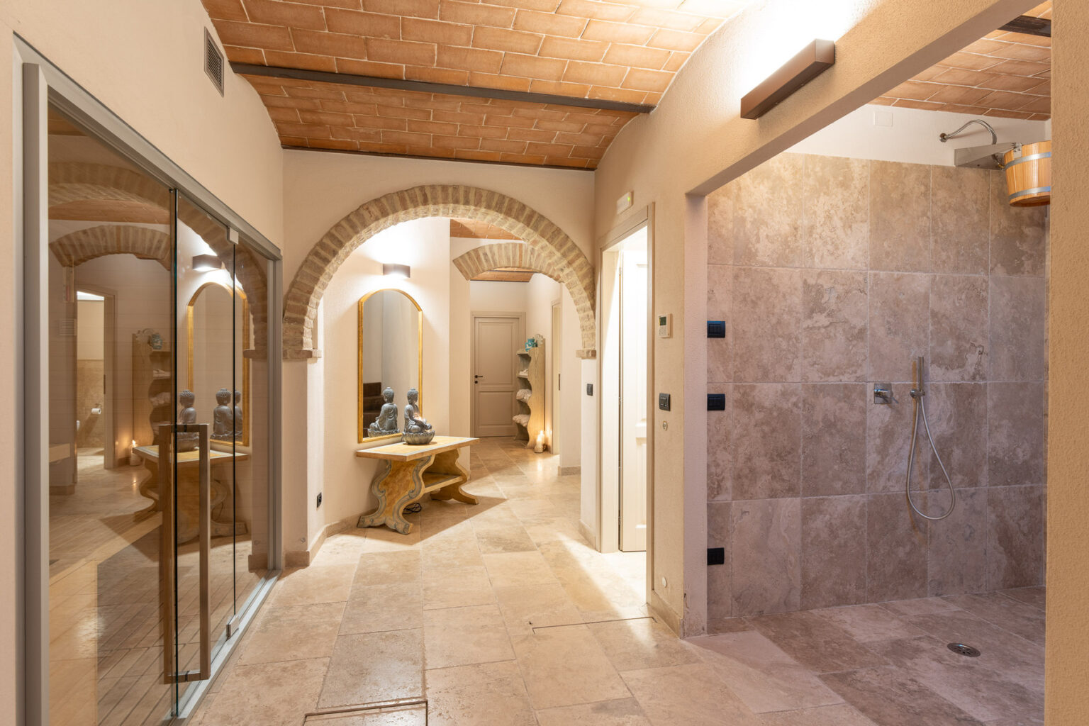 Luxurious bathroom interior featuring arched doorways, natural stone tiles, a spacious walk-in shower, and elegant lighting, designed for relaxation and comfort. | Only on SopranoVillas
