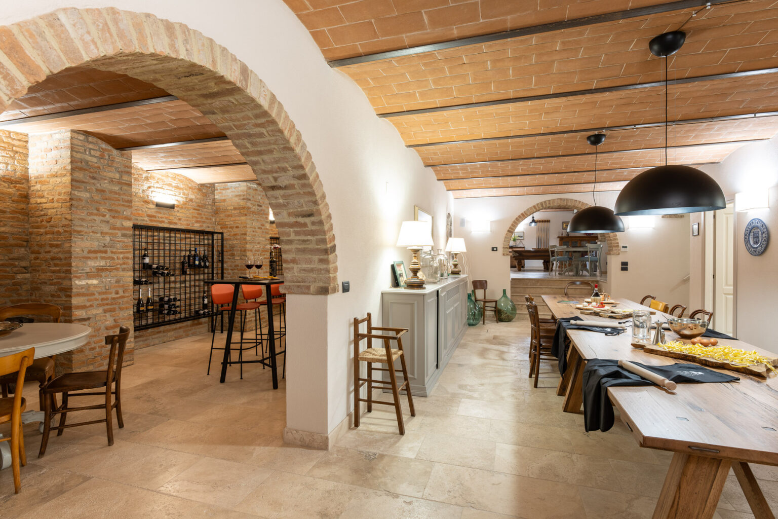 Modern rustic dining area featuring arched brick details, wooden furniture, and a wine storage space, creating a warm and inviting atmosphere. | Only on SopranoVillas