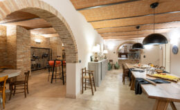 Modern rustic dining area featuring arched brick details, wooden furniture, and a wine storage space, creating a warm and inviting atmosphere.