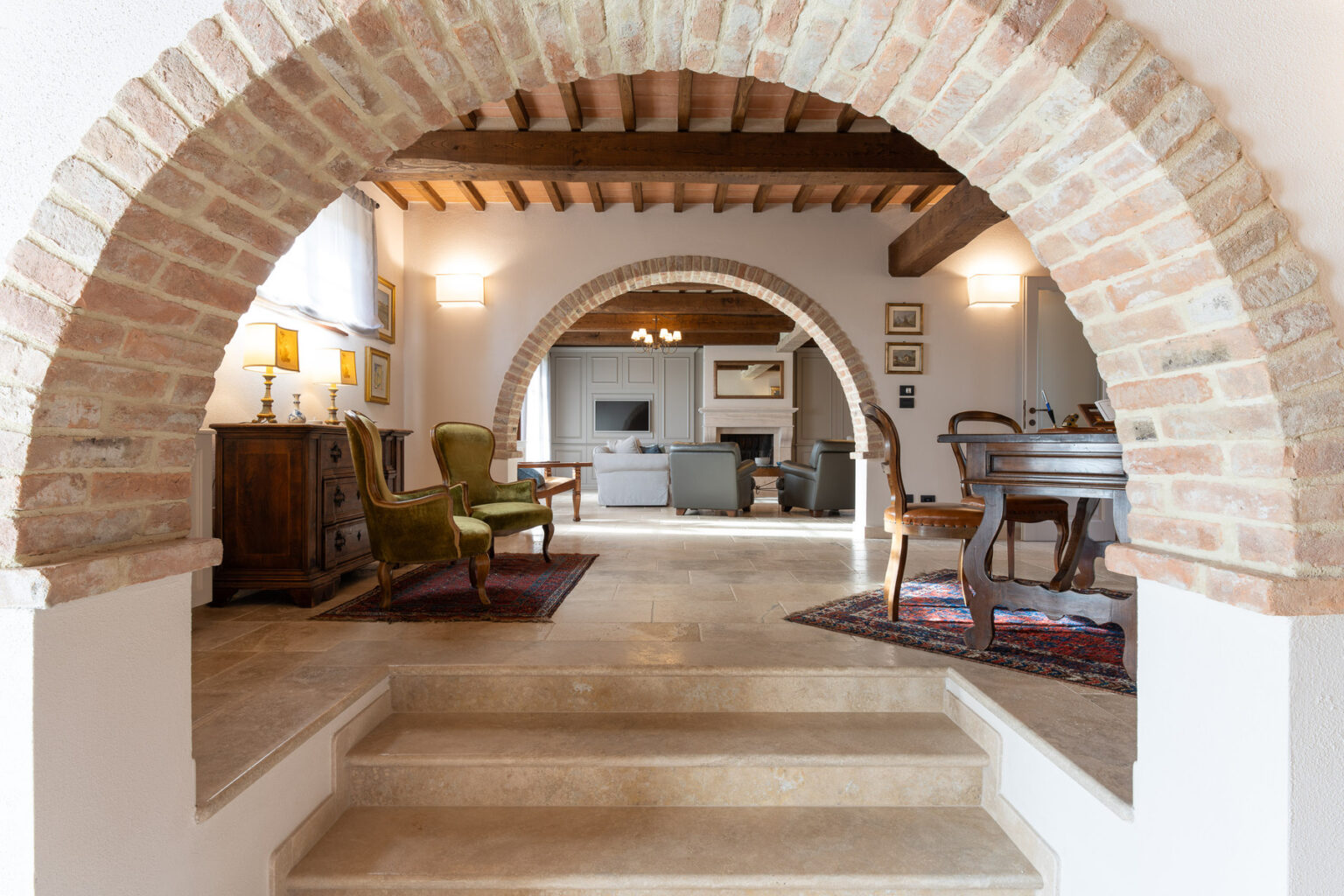 Interior view of a stylish living space featuring brick arches, wooden beams, and elegant furniture, showcasing a cozy and inviting atmosphere. The design blends modern comfort with classic architectural elements. | Only on SopranoVillas