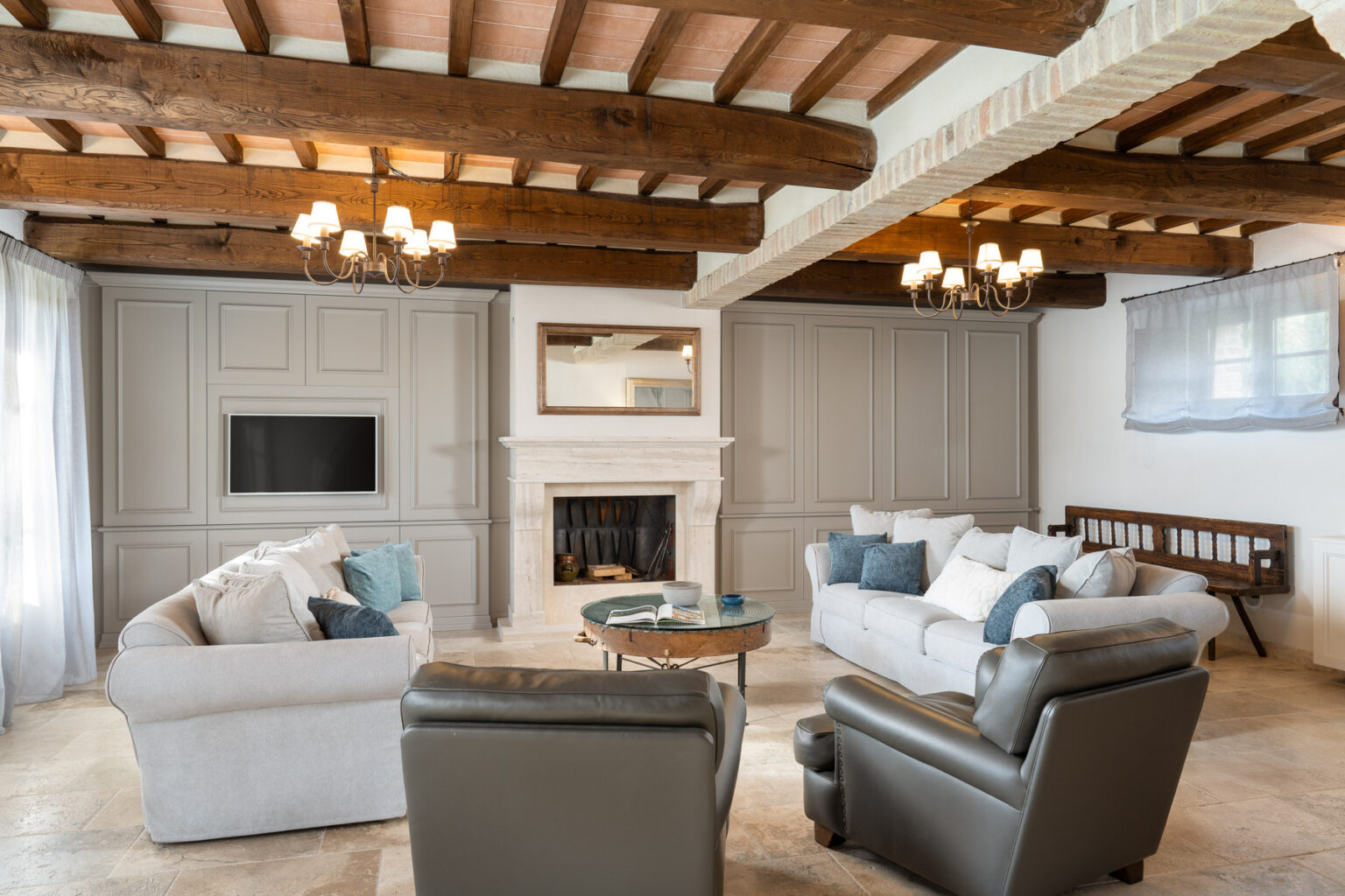 Modern living room with wooden beams, neutral color palette, comfortable sofas, and a cozy fireplace, featuring stylish decor and natural light. | Only on SopranoVillas